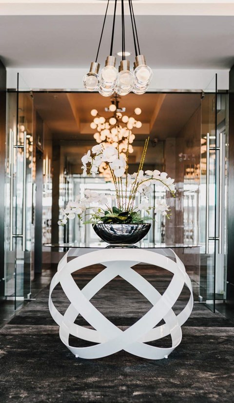 a white table with a flower arrangement in a room with glass doors